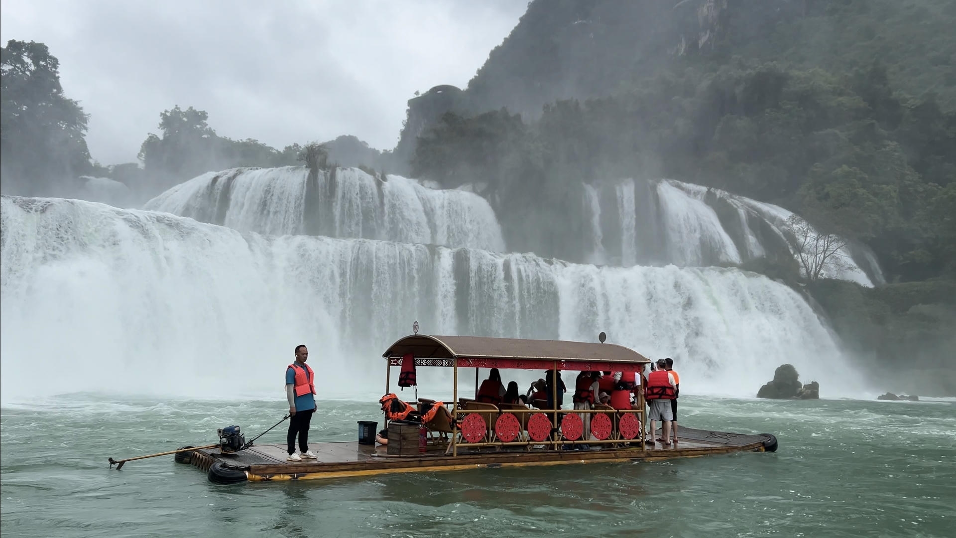 Tour boat on the jade-green river in front of Bản Giốc Waterfall in Cao Bằng, Vietnam